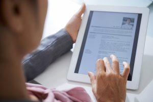 Hand of employer scrolling in touchpad while looking through information about an applicant in electronic resume