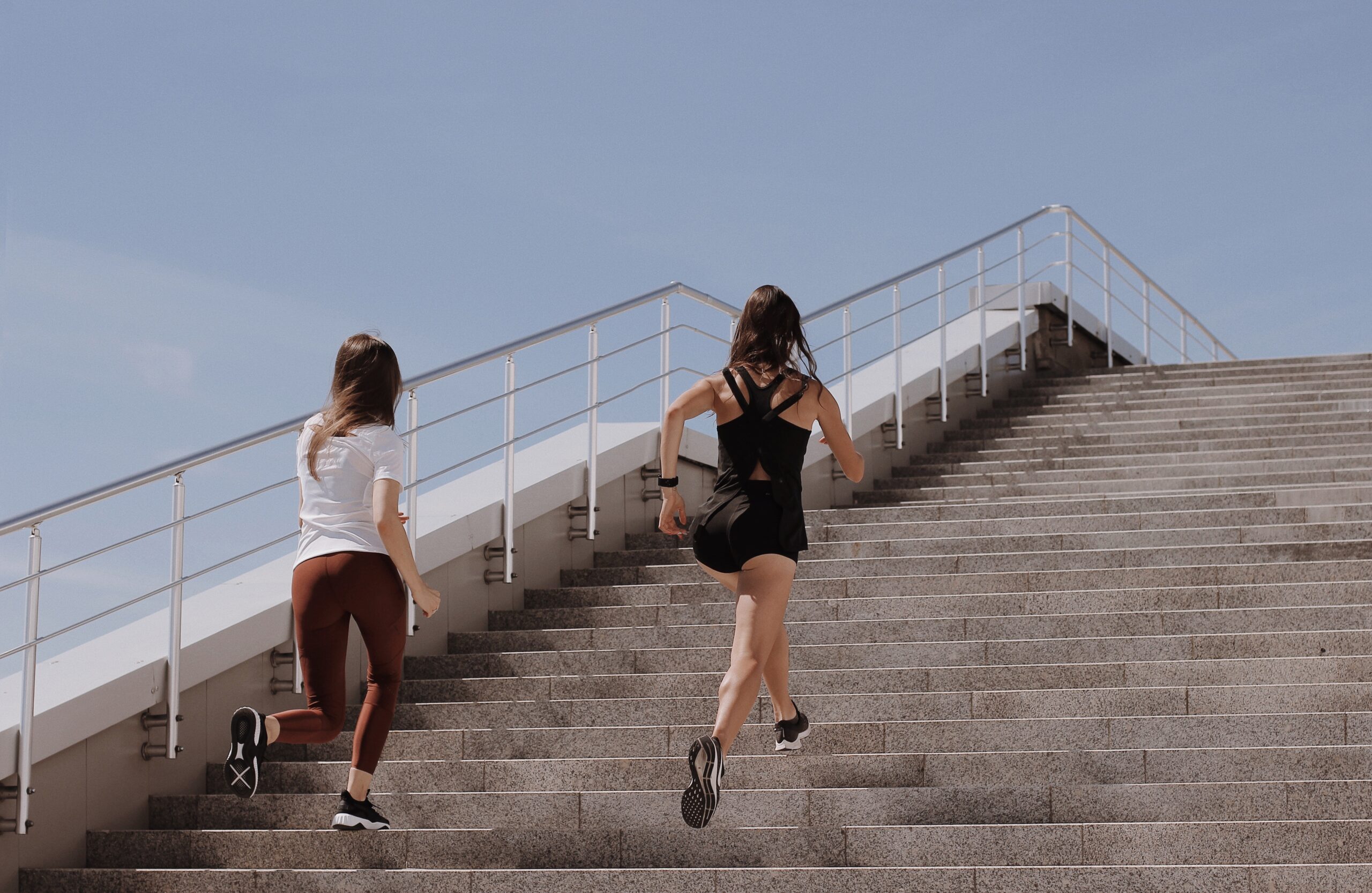 Two women running up stairs outside
