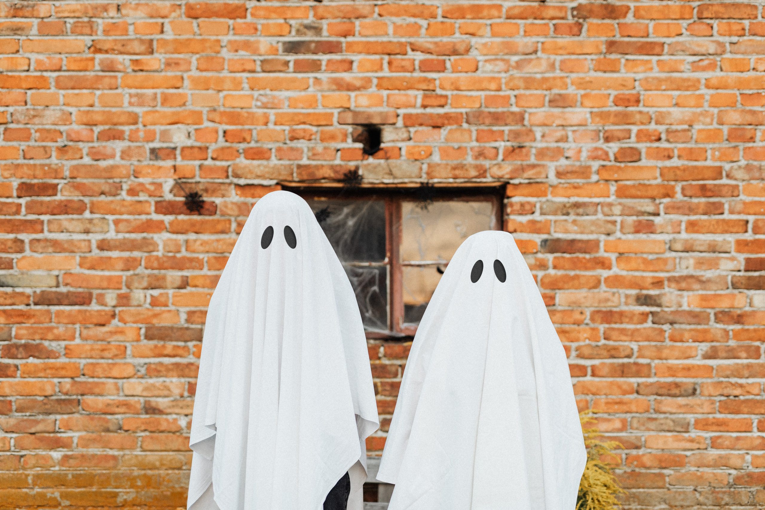 two ghosts in front of a brick wall