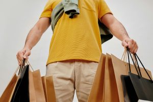 Man in yellow shirt holding several black friday shopping bags